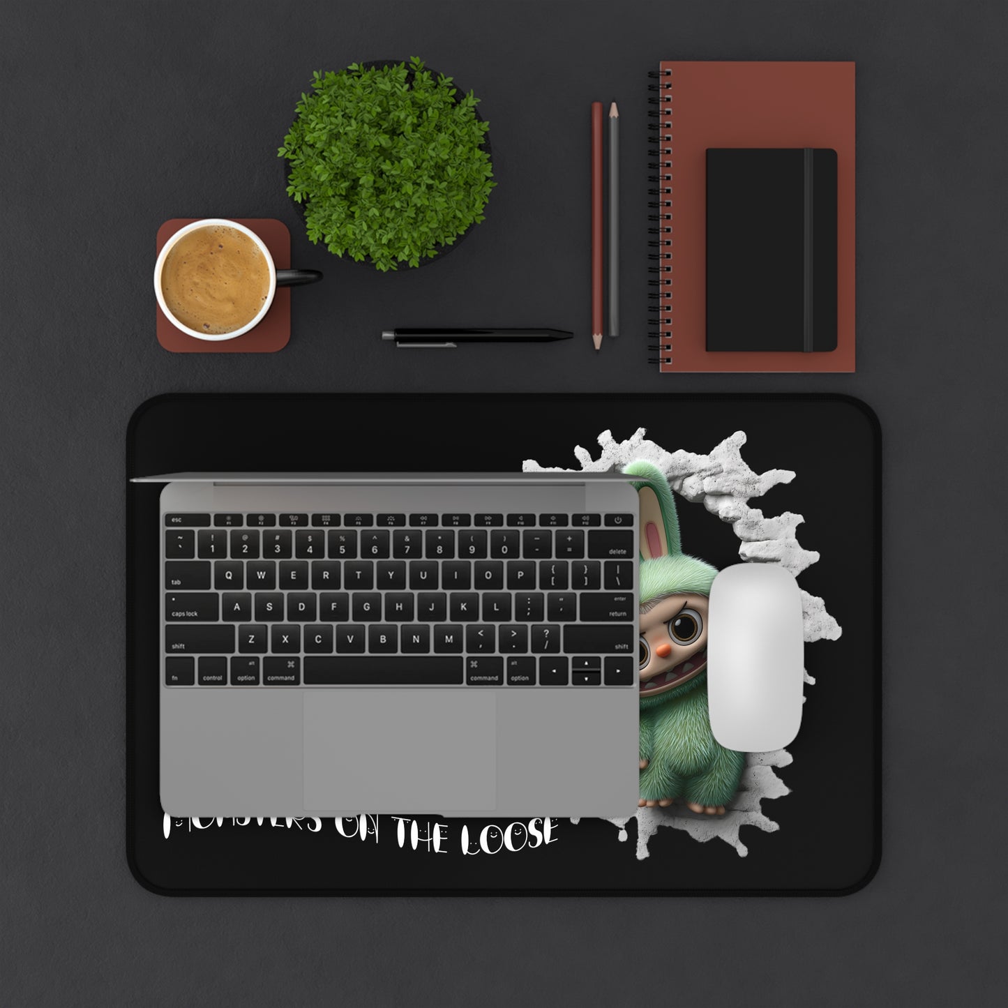 Laptop with a 'Baby Yoda on the Loose' design on a dark surface with a cup, plant, and notebook.
