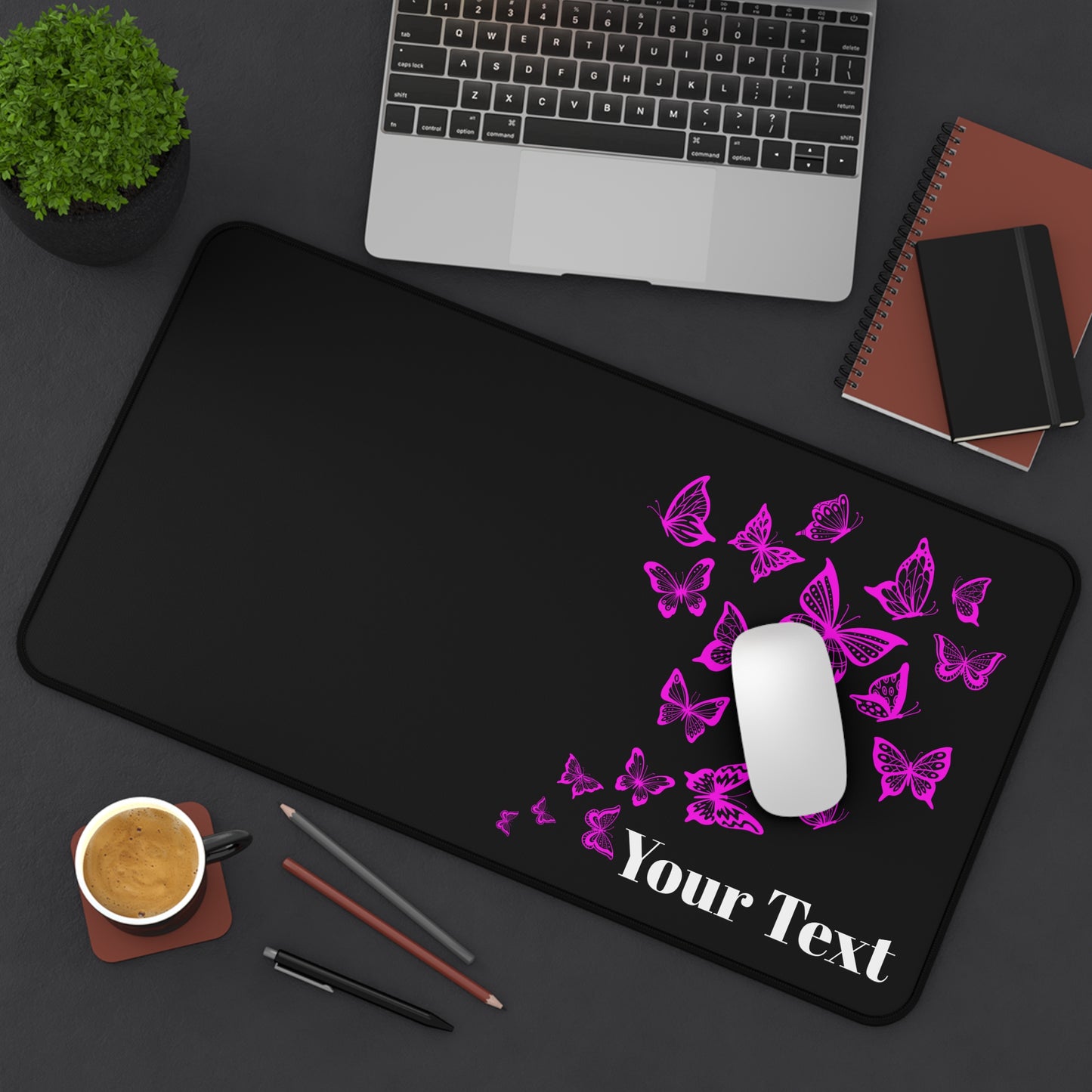 Black desk mat with pink butterflies and customizable text, placed on a desk with a laptop and office supplies.