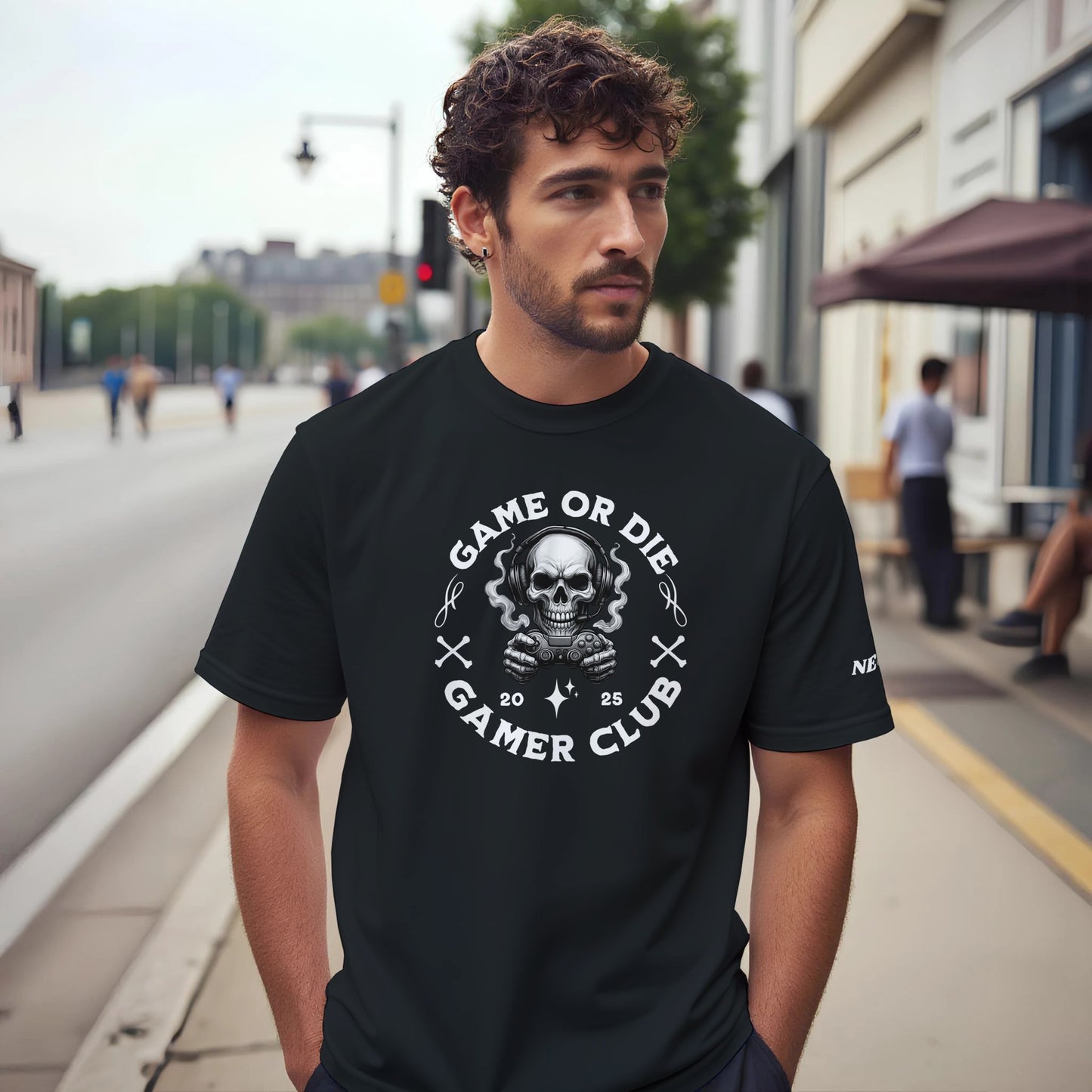 Man wearing a black t-shirt with 'Game or Die Gamer Club' design on a city street.