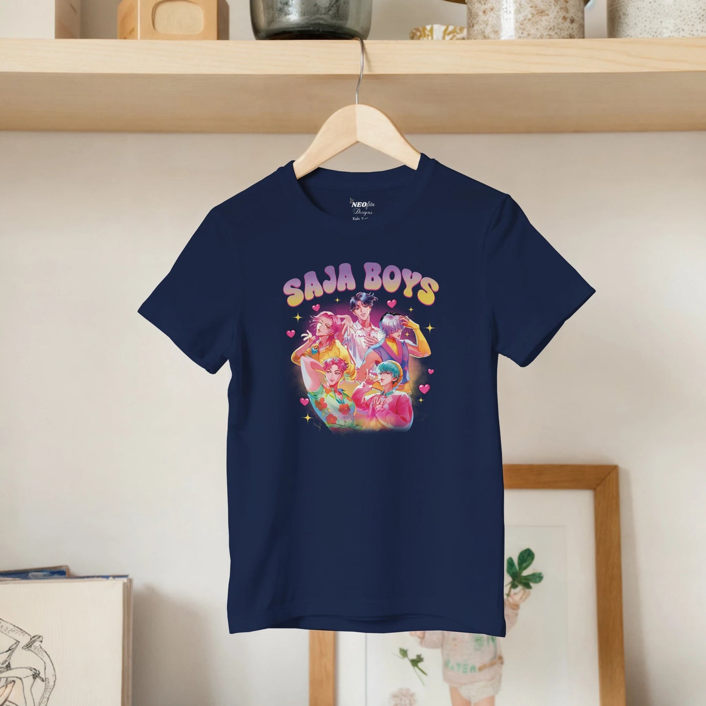 Navy blue t-shirt with colorful graphic and 'SAJA BOYS' text on a hanger against a neutral wall.