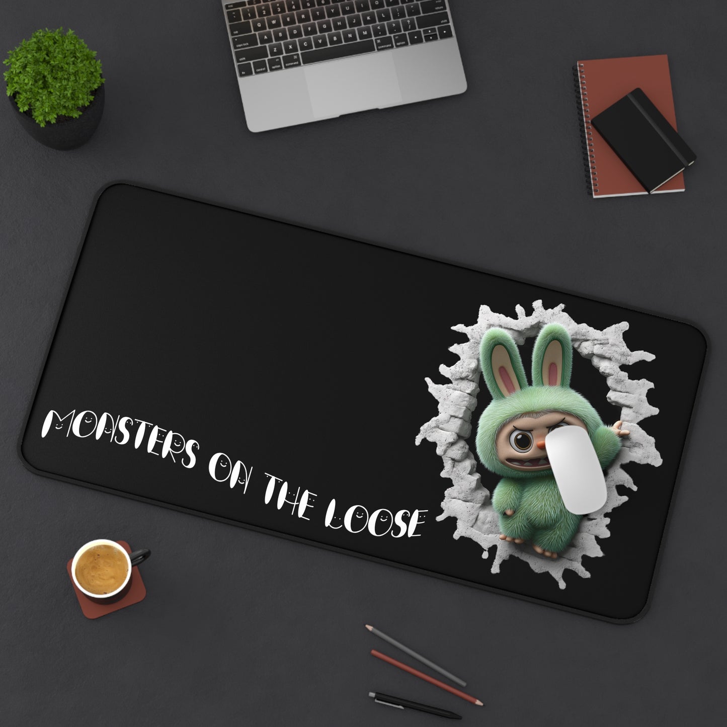 Desk mat with cartoon character and text 'Monsters on the Loose' on a dark surface.