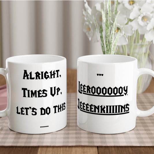 Two white mugs with humorous text on a table with a checkered tablecloth and flowers in the background.