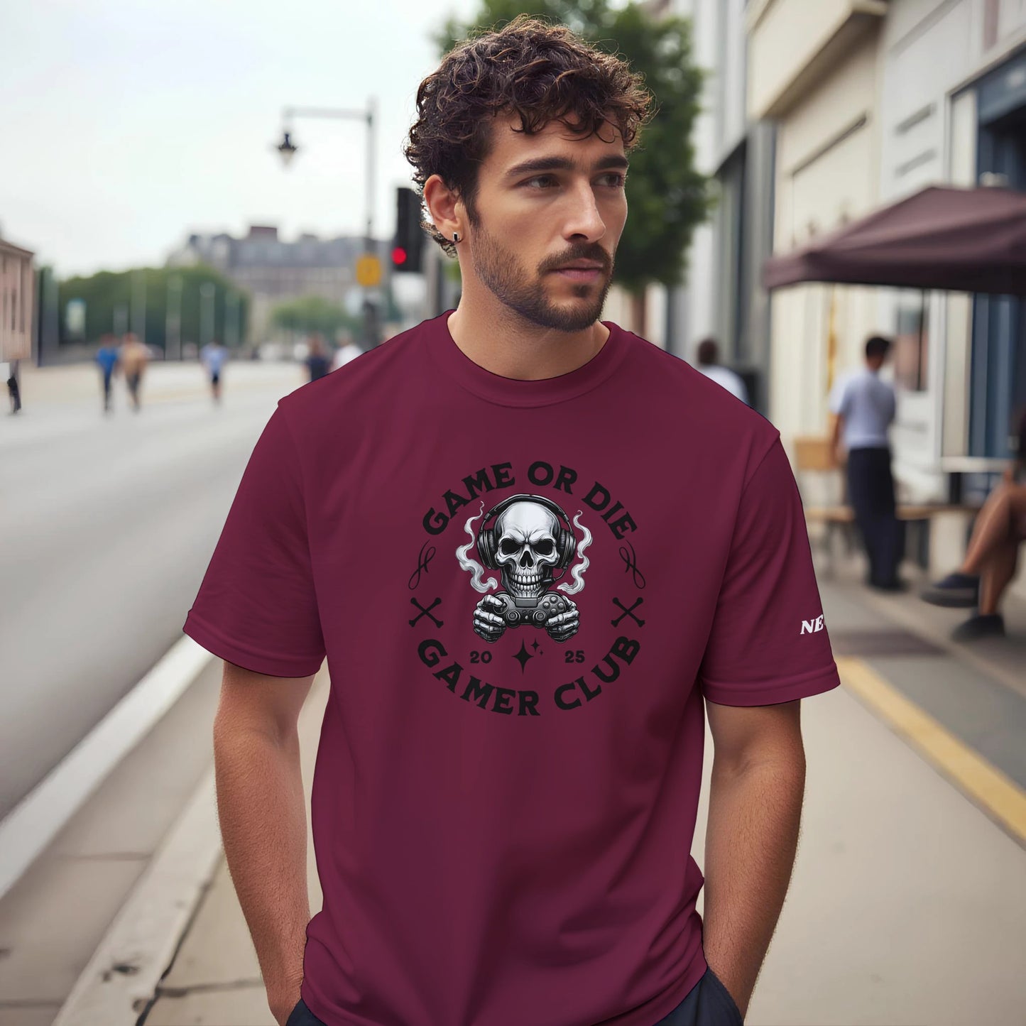 Man wearing a maroon t-shirt with a graphic design on a city street.