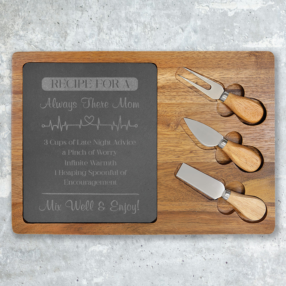 Wooden cutting board with engraved text and three cheese knives on a gray surface