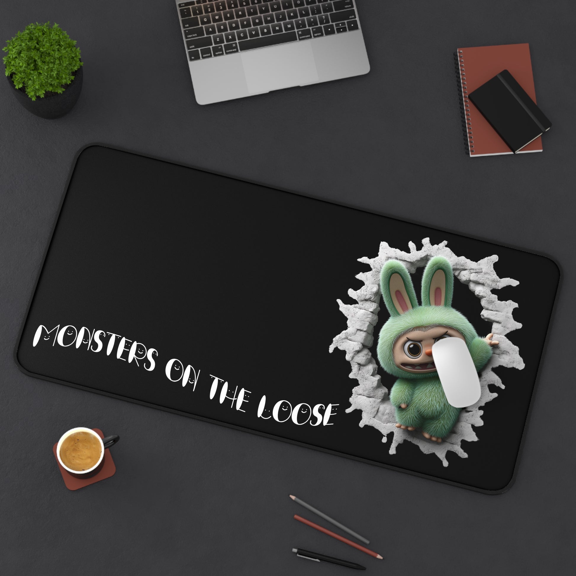 Desk mat with cartoon character and text 'Monsters on the Loose' on a dark surface.