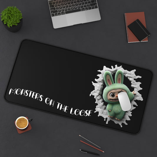 Desk mat with cartoon character and text 'Monsters on the Loose' on a dark surface.