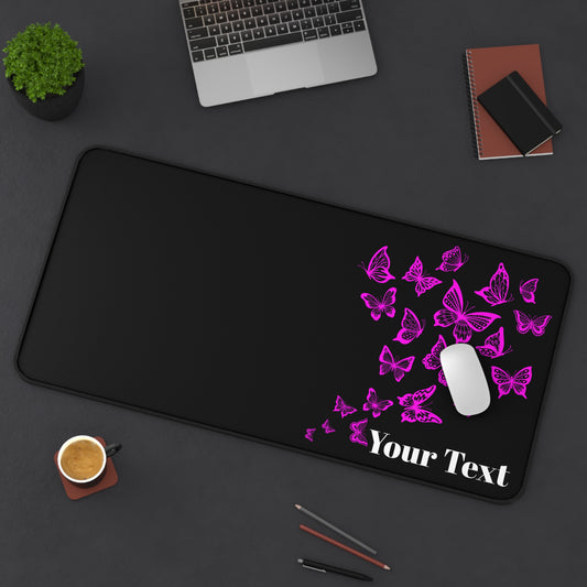 Black desk mat with pink butterflies and 'Your Text' placeholder on a dark surface with office items.