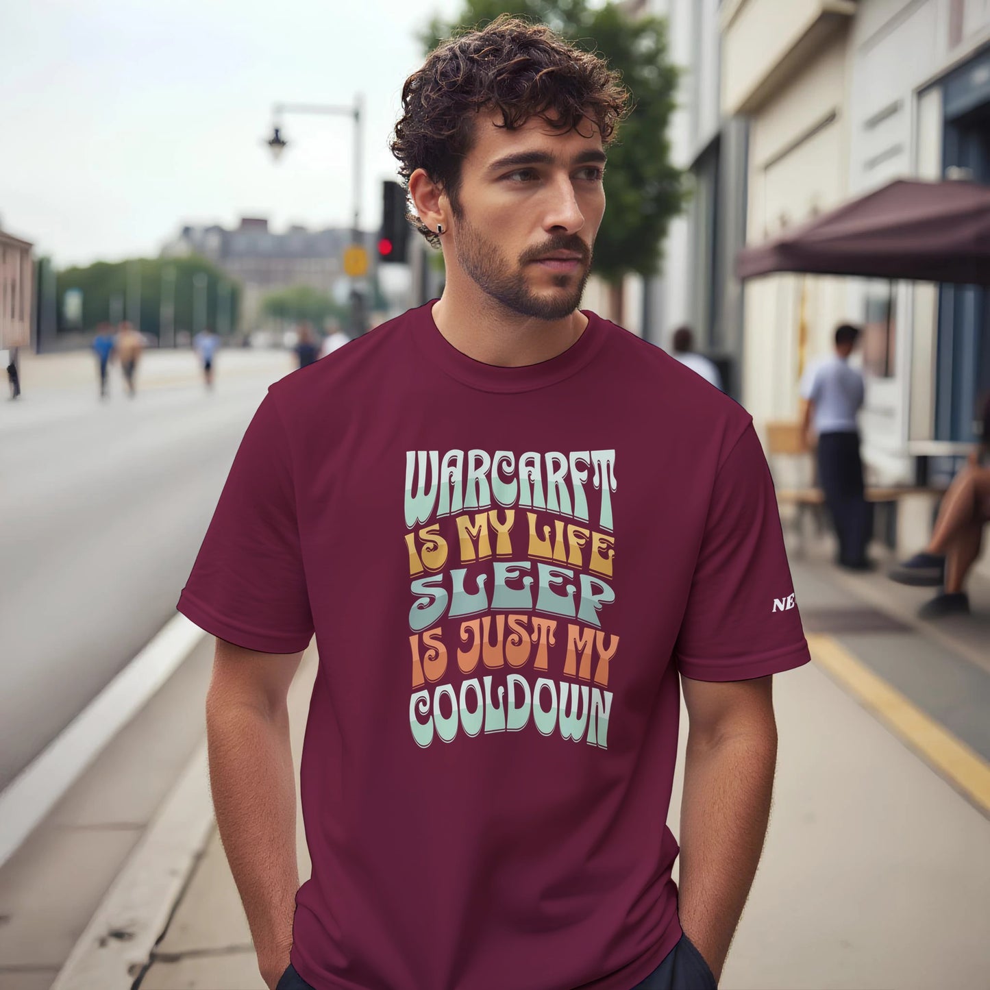 Man wearing a maroon t-shirt with colorful text on a city street